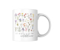 Preview: Weiße Keramiktasse mit filigranem Wildblumenmotiv und dem Zitat „You belong among the wildflowers“ auf neutralem Hintergrund.